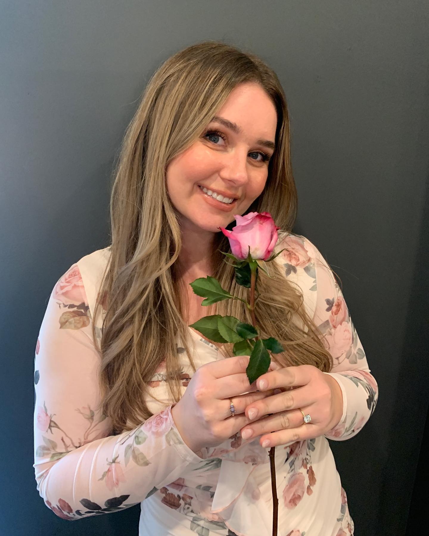 Caitlin holding a pink rose with a warm smile.
